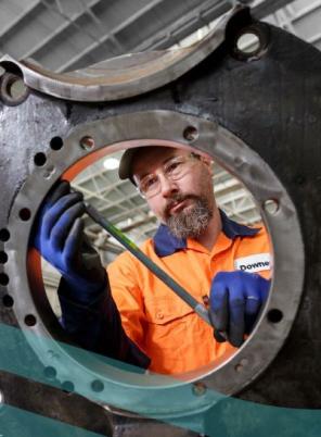 Image of rail worker measuring the size of a train wheel.